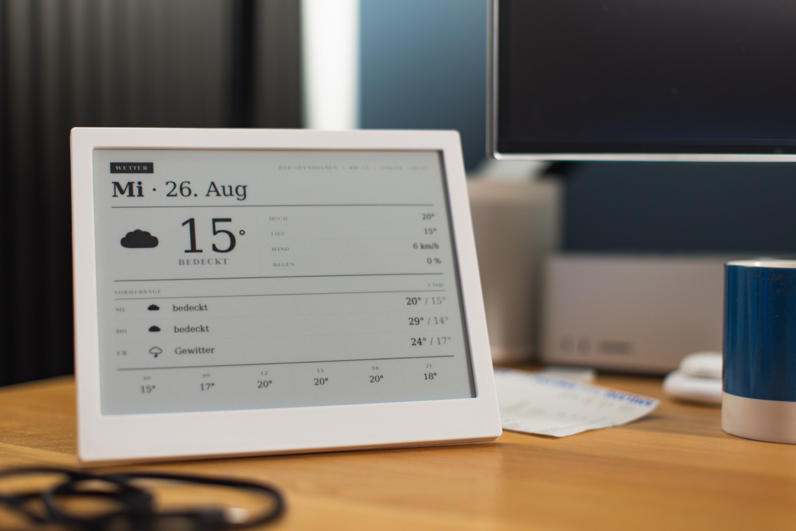 TRMNL X von vorne auf dem Schreibtisch, auf dem E-Ink-Display läuft der Wetter-Screen der Almanach-Suite